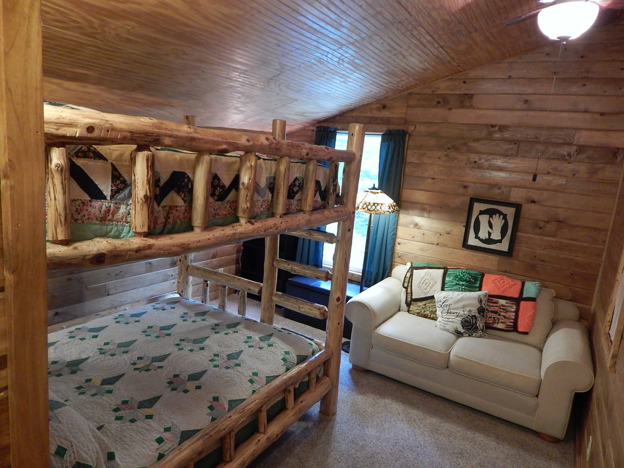 Cedar log bunk bed with love seat next to sunny window.