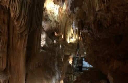 Inside of a dark cave with accent lighting showing calcium deposits