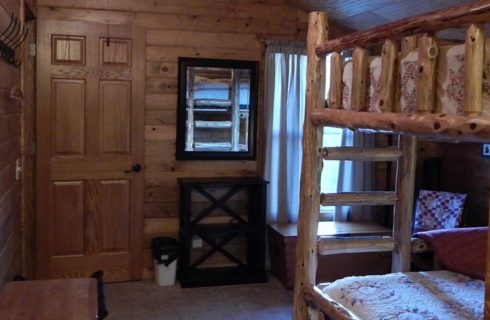 Bedroom with carpet, wood paneling on the walls, and wooden bunk bed