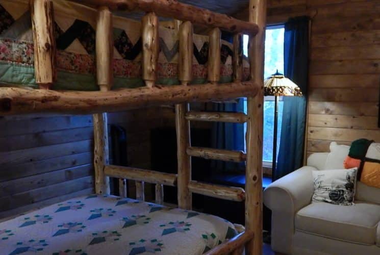 Bedroom with carpet, wood paneling on the walls, wooden bunk bed, and love seat