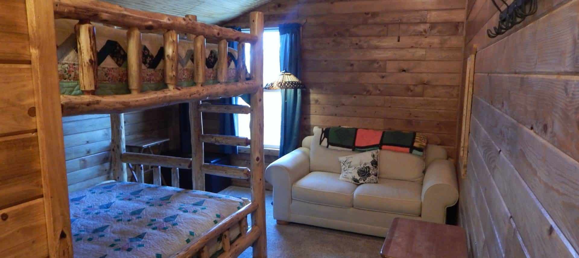 Bedroom with carpet, wood paneling on the walls, wooden bunk bed, and love seat