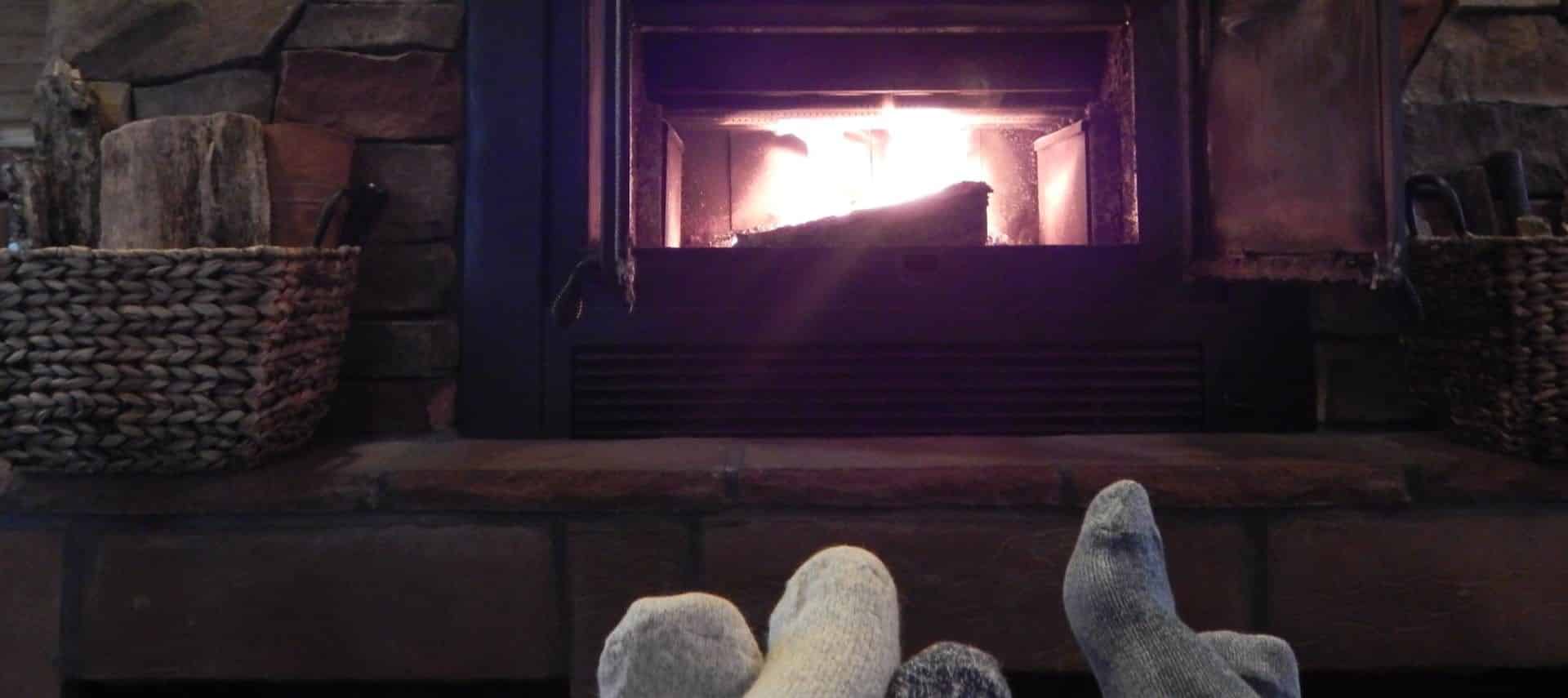 View of a lighted fireplace in the background and some feet in socks near by